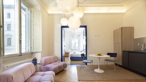Een moderne woonkamer met een bank, een eettafel met stoelen en een keuken met kasten.