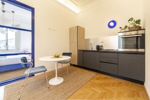 A modern kitchen with a built-in oven, a dining area with a table and chairs, and a large window with a view.