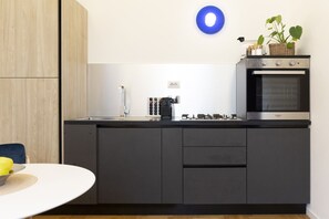 A modern kitchen with a built-in oven, a coffee machine, and a wall-mounted light fixture.