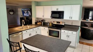 A compact kitchen with white cabinets, a microwave, an oven, and a sink.
