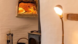 Une pièce chaleureuse avec un poêle à bois, une lampe et un panier de bois de chauffage.