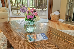 Una mesa de madera con un jarrón de vidrio que contiene flores y un libro titulado 'Blue Ridge Parkway'.