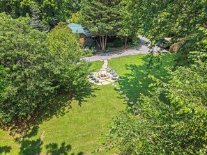 A residential property with a well-maintained lawn, a stone fire pit, and a wooden deck.