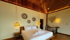 A spacious bedroom with a large bed, wooden flooring, and a desk area. - Ten Moons Sunset Villas (Koh Lipe)
