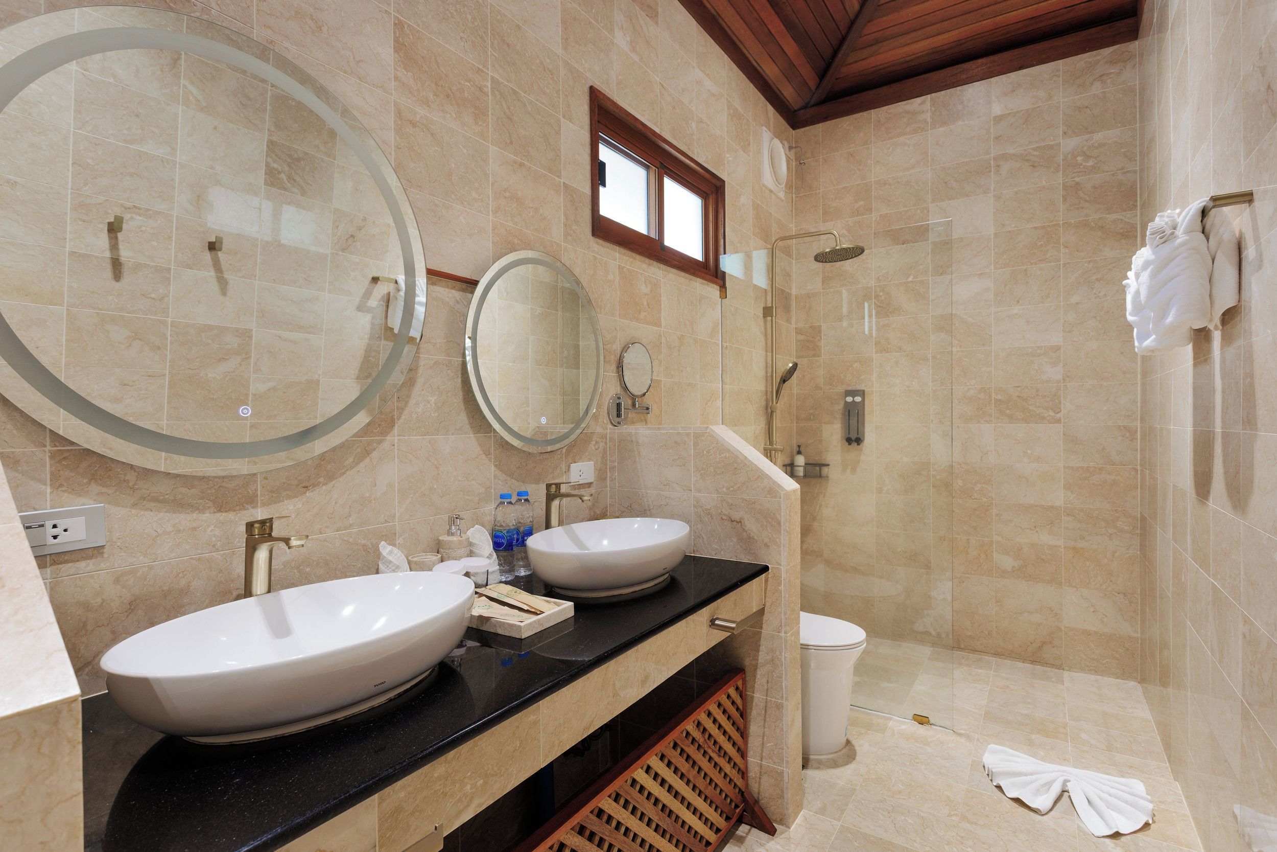 Une salle de bain avec deux lavabos, un grand miroir, une douche et des toilettes.