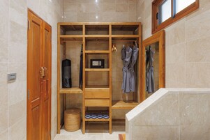 A walk-in closet with wooden shelving, a safe, and a shoe rack.