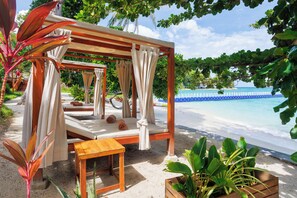 A beachside lounge with a wooden canopy, cushioned seating, and a view of the ocean. - Ten Moons Sunset Villas (Koh Lipe)