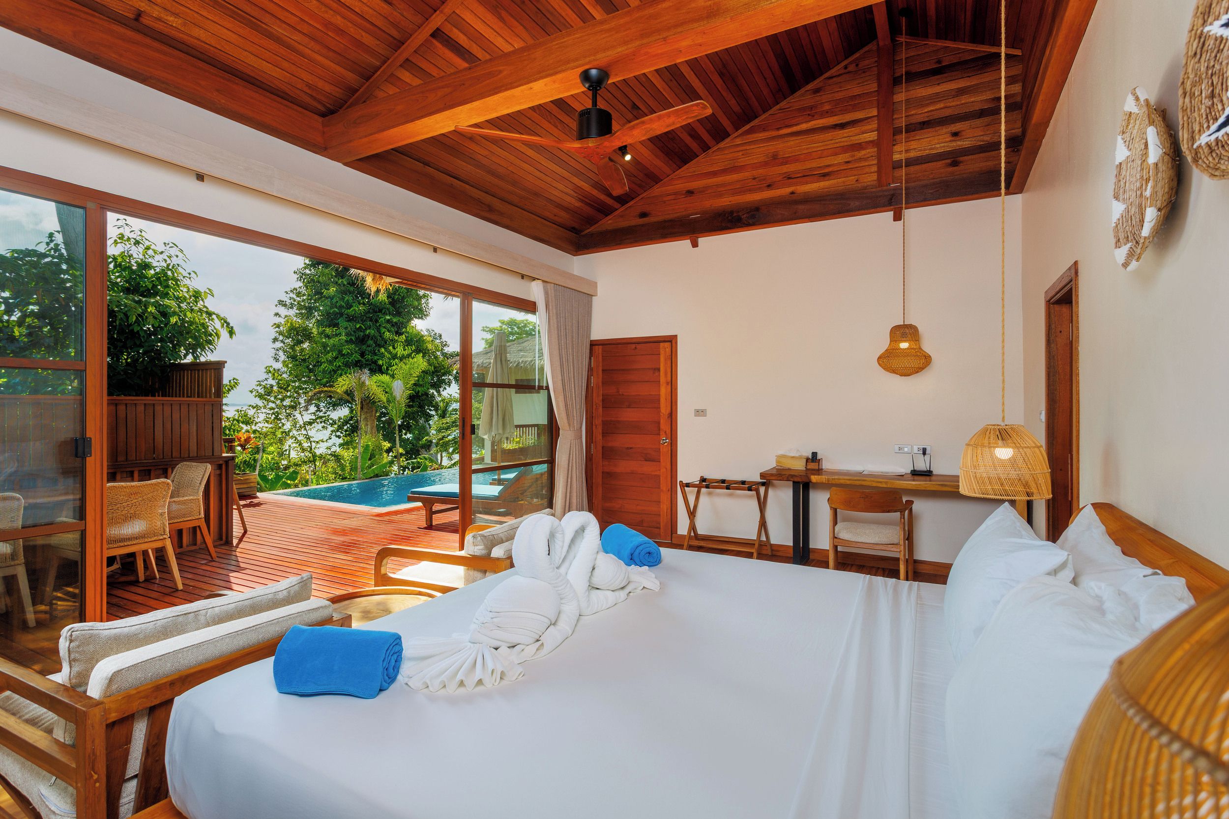 Ein Schlafzimmer mit einem großen Bett, einem Schreibtisch und Blick auf ein Außenbecken.