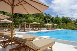 A poolside area with lounge chairs, umbrellas, and a clear blue pool. - Ten Moons Sunset Villas (Koh Lipe)
