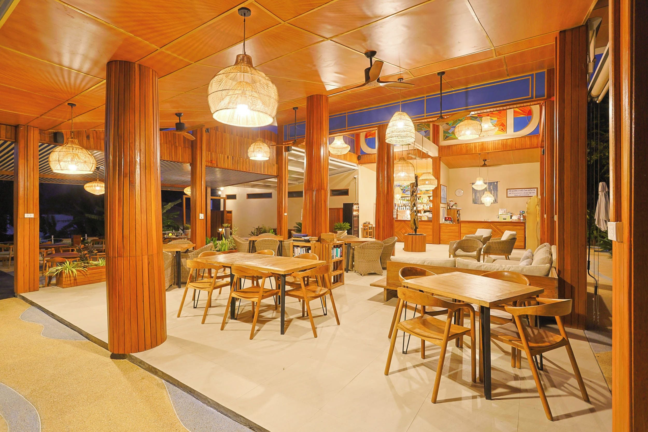A spacious indoor area with wooden furniture, including tables and chairs, and hanging pendant lights.