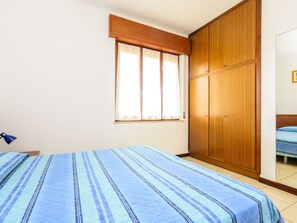 A bedroom with a bed, a wardrobe, and a window with curtains.