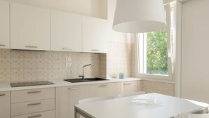 Une cuisine moderne avec des meubles blancs, un évier noir et une fenêtre qui laisse entrer la lumière naturelle.