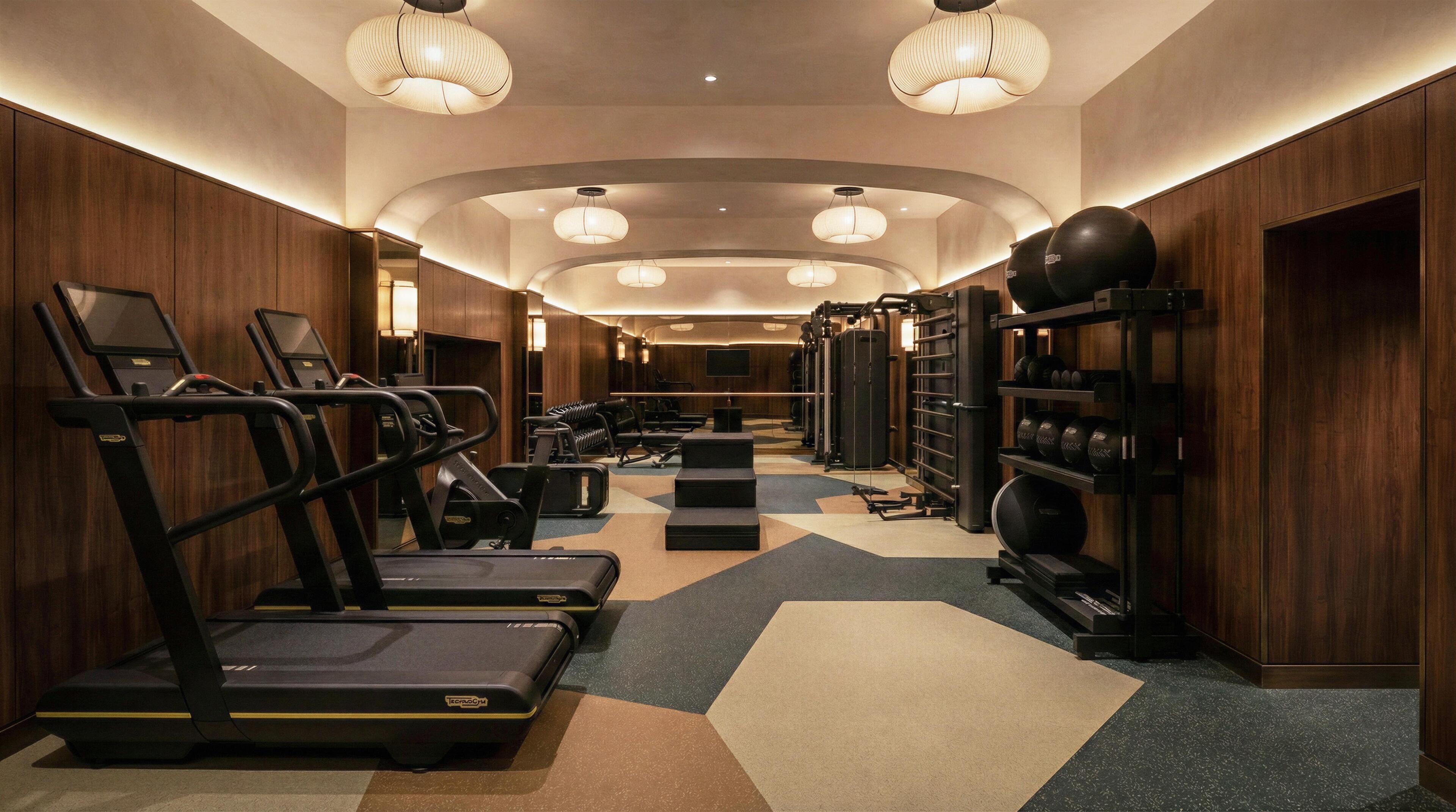 A gym with treadmills, weight machines, and a mirrored wall.