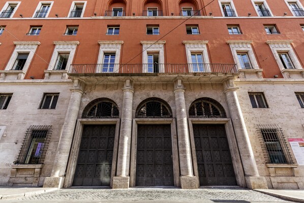 A building with a red facade, large arched doors, and multiple windows with balconies.