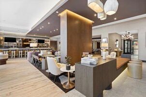 A modern lobby with a reception desk, seating areas, and a bar.