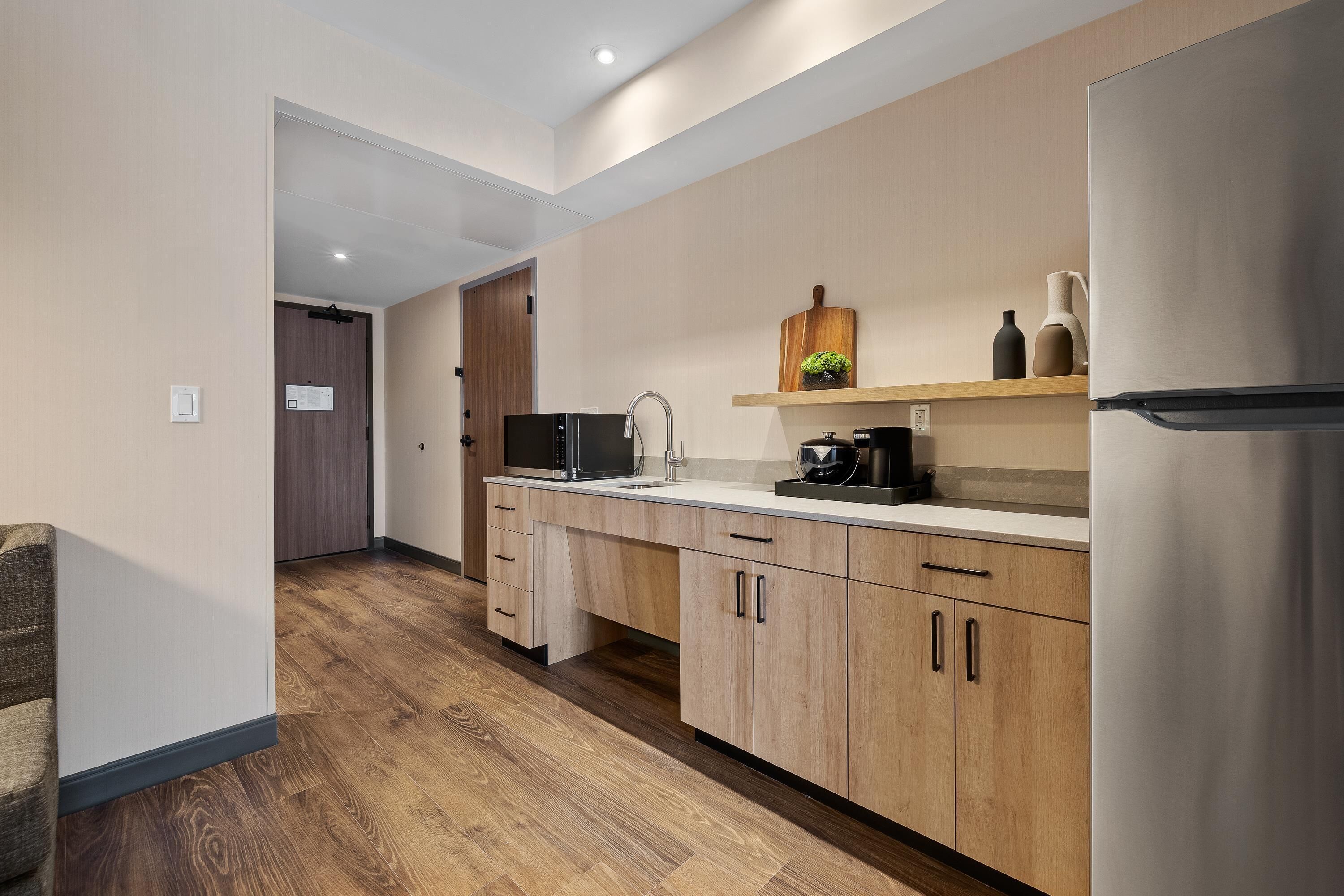 Una cocina moderna con armarios de madera, un refrigerador de acero inoxidable y un microondas.