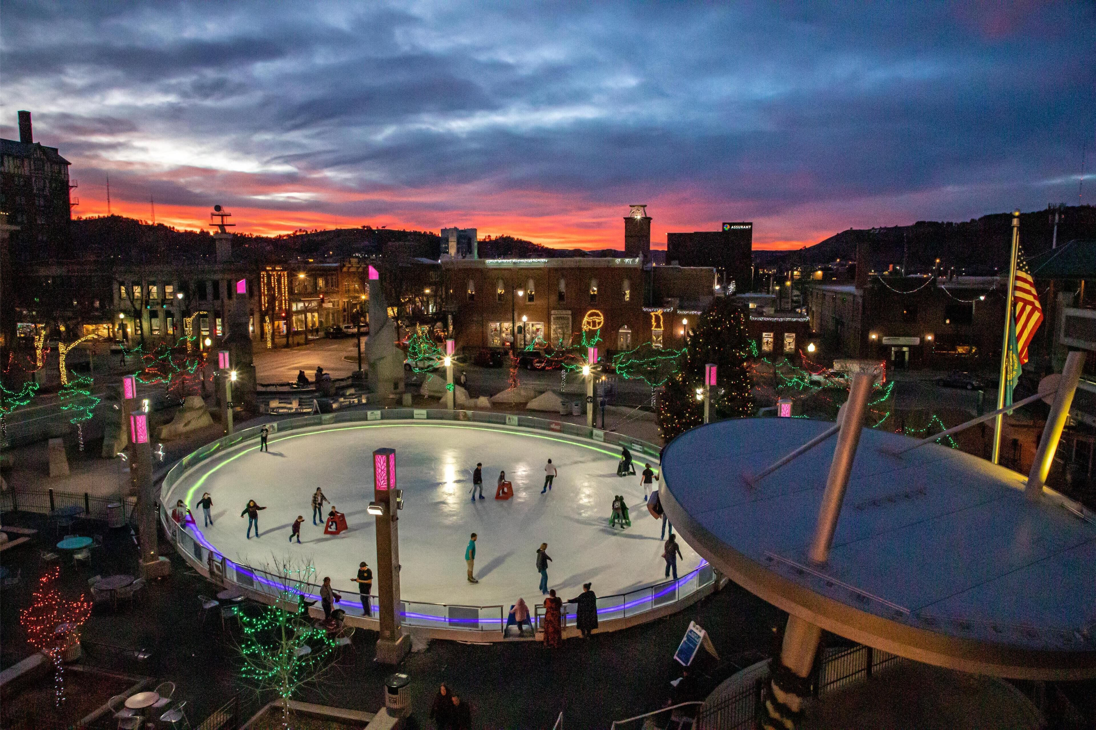 Una pista de hielo al aire libre rodeada de edificios con decoraciones navideñas.