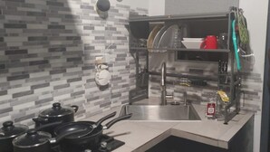 A kitchen with a modern design, featuring a tiled backsplash, a stainless steel sink, and a dish drying rack.