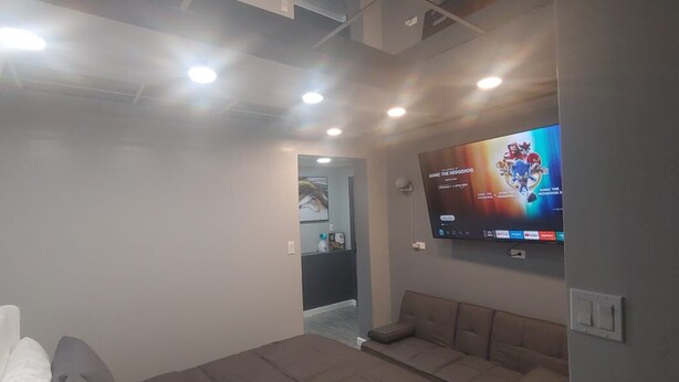 A modern hotel room with a large bed, a sofa, and a flat-screen TV mounted on the wall.