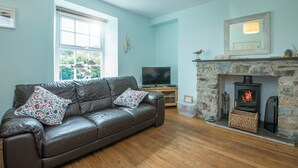 A living room with a brown leather sofa, a stone fireplace, a television, and a window with blinds. - Llys Bonfyl, Holiday Cottage St Dogmaels, Sleeps 6, 3 bedrooms,  bathrooms (Cardigan)