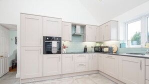 A modern kitchen with light-colored cabinets, a built-in oven, and a window providing natural light. - Llys Bonfyl, Holiday Cottage St Dogmaels, Sleeps 6, 3 bedrooms,  bathrooms (Cardigan)