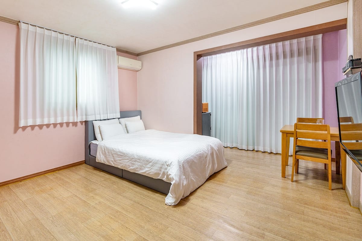 A bedroom with a bed, a desk, and a chair.