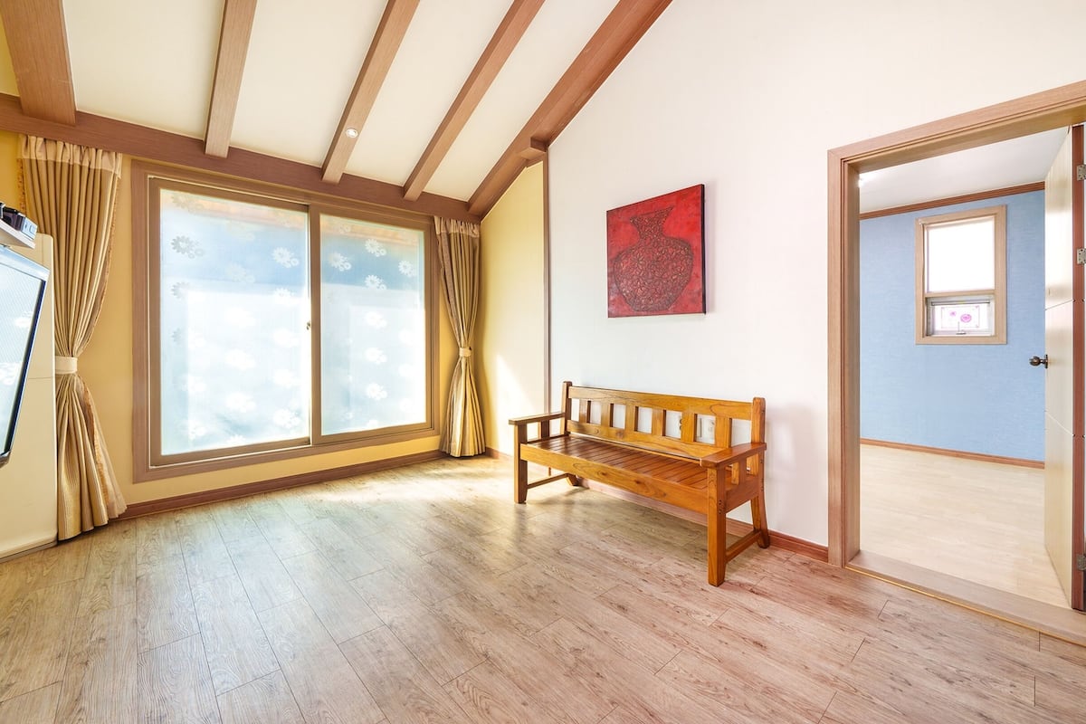 A room with wooden flooring, a bench, a sliding glass door, and a framed picture on the wall.