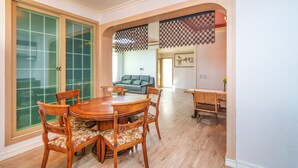 A dining area with a wooden table and chairs, a sofa in the background, and a sliding glass door. - Gyeongju Clearmorning Petfriendlypension (Gyeongju)