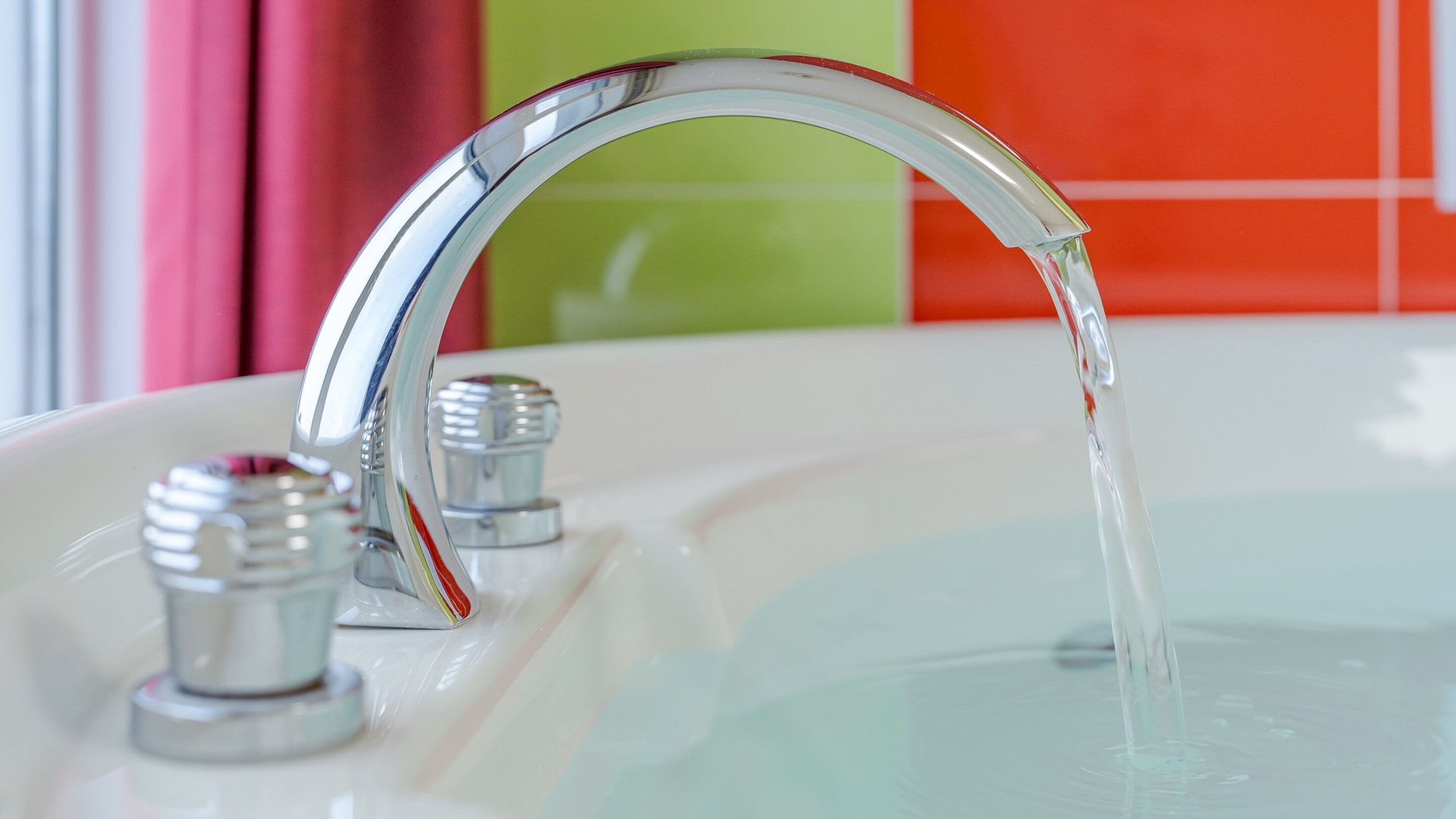 A modern bathroom sink with a chrome faucet and clear running water.