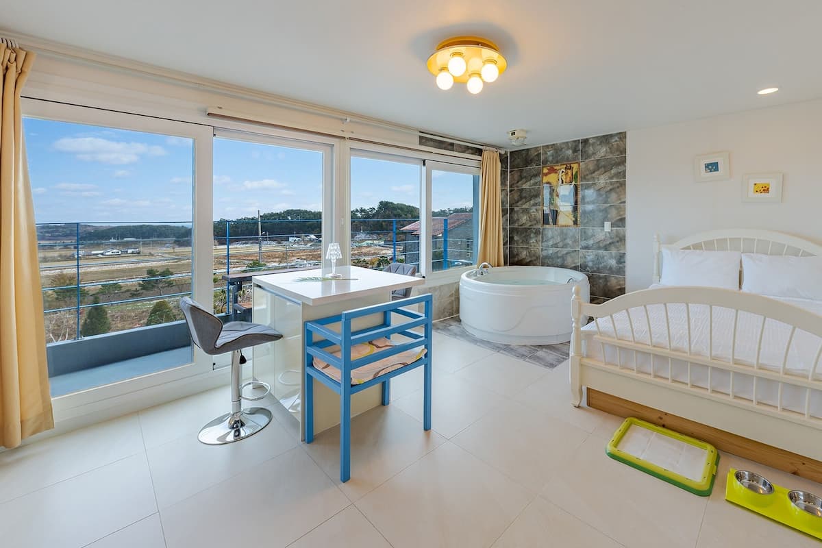 Une chambre moderne avec une grande fenêtre, un bureau, un lit et une baignoire.
