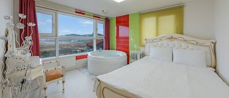 Une chambre à coucher avec un grand lit, une fenêtre donnant sur des champs, une baignoire et un fauteuil décoratif.