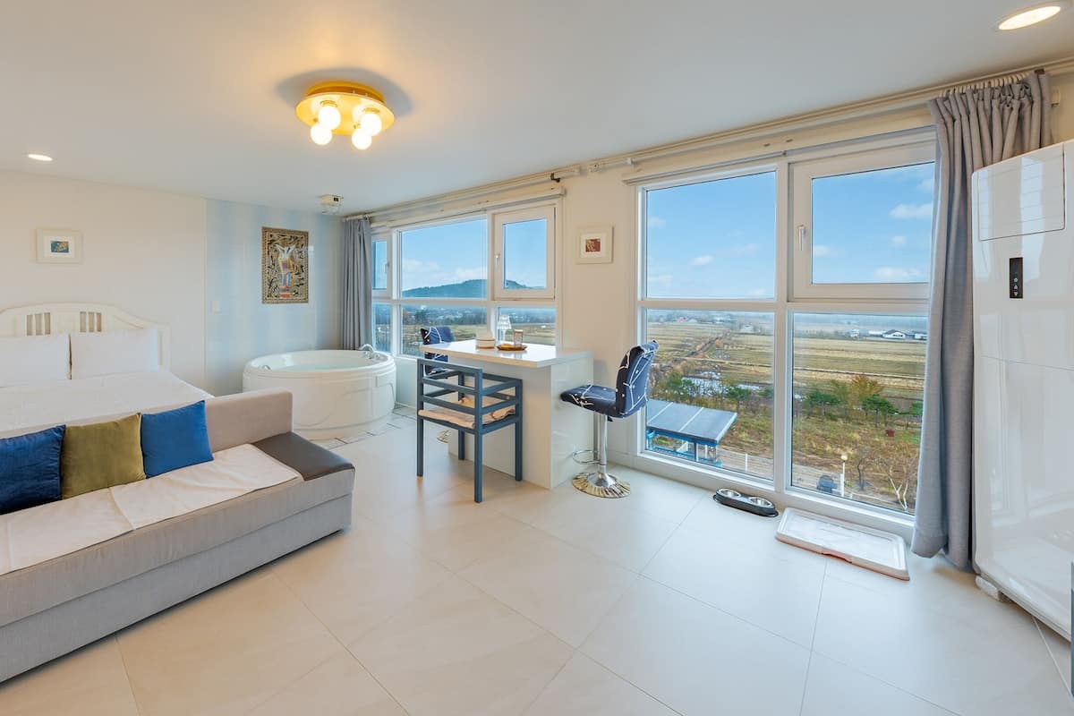Une chambre d’hôtel moderne, dotée d’un grand lit, d’un canapé, d’un bureau et offrant une vue sur la campagne.