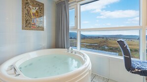 Un baño con una bañera grande, una ventana que da a campos y un adorno en la pared.