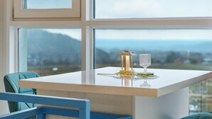 Una mesa con una vela, un vaso y una planta en una habitación con ventanas amplias.