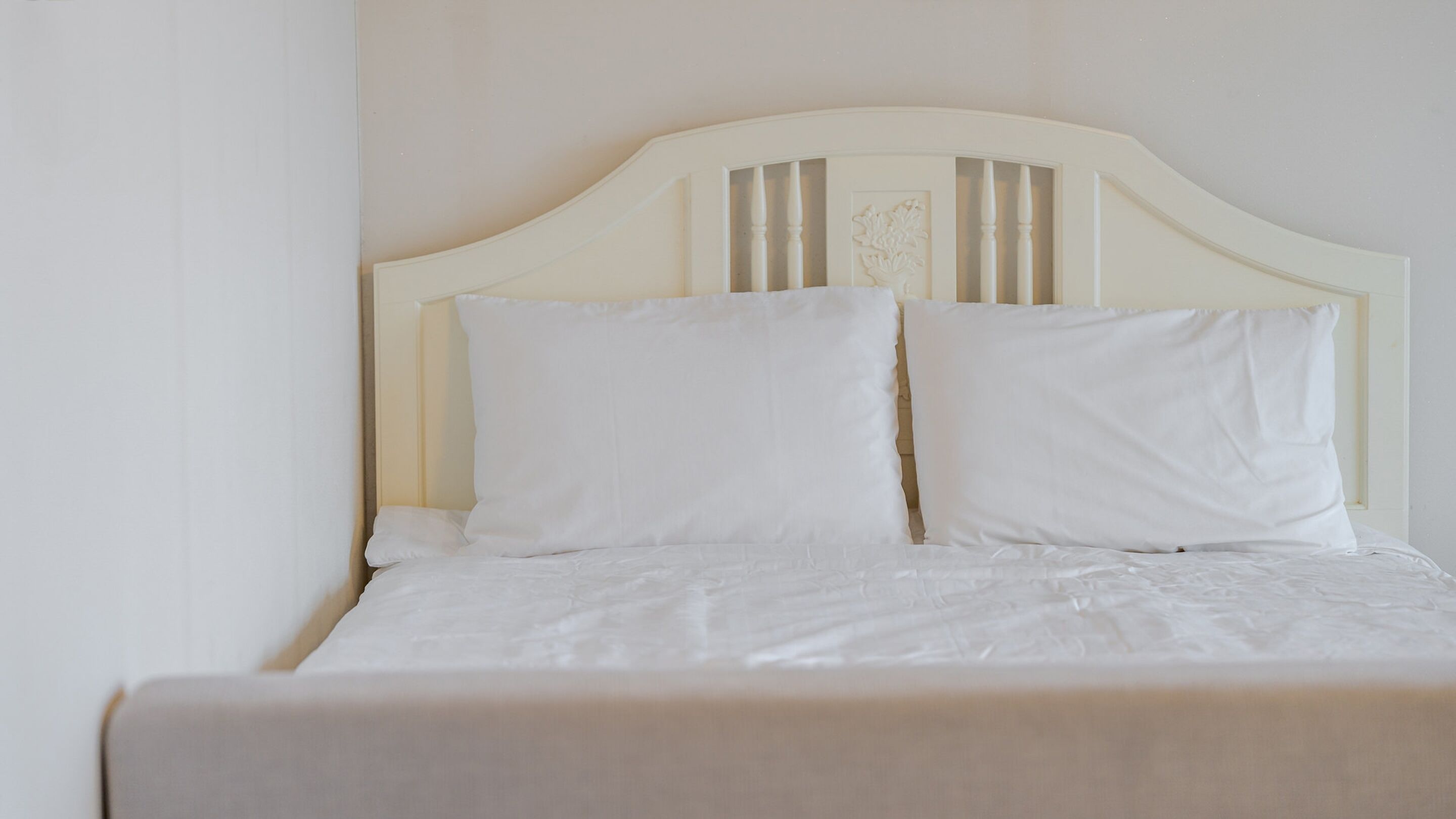 A bed with a white headboard and two pillows.