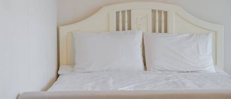 A bed with a white headboard and two pillows.