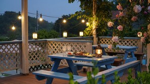 An outdoor dining area with wooden tables and benches, string lights, and a lantern. - Yangyang Monti Pet Spa Pension (Yangyang)