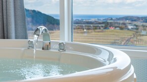 A bathroom with a bathtub, a window, and a view of a distant landscape. - Yangyang Monti Pet Spa Pension (Yangyang)