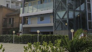 A multi-story building with a glass facade, balconies on each floor, and a modern architectural design. - Nice apartment for 4 people with WIFI, A/C, TV, balcony and pets allowed (Lignano Sabbiadoro)