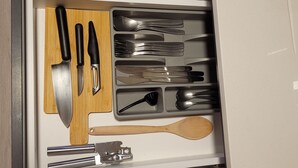 Uma gaveta com diversos utensílios de cozinha, incluindo facas, colheres e uma espátula.