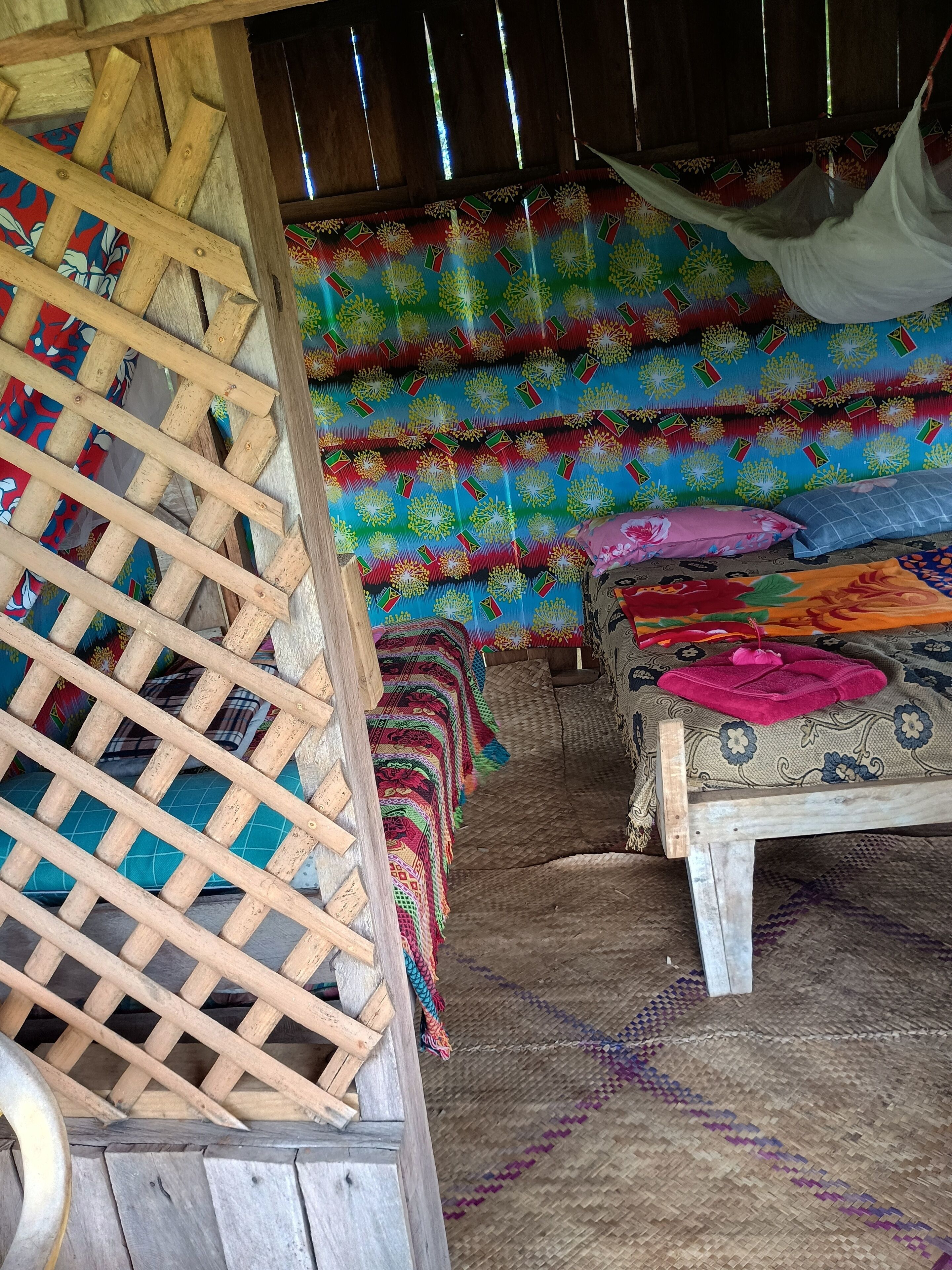 Una habitación rústica con una escalera de madera, una cama con ropa de cama colorida y un tapete tejido en el suelo.