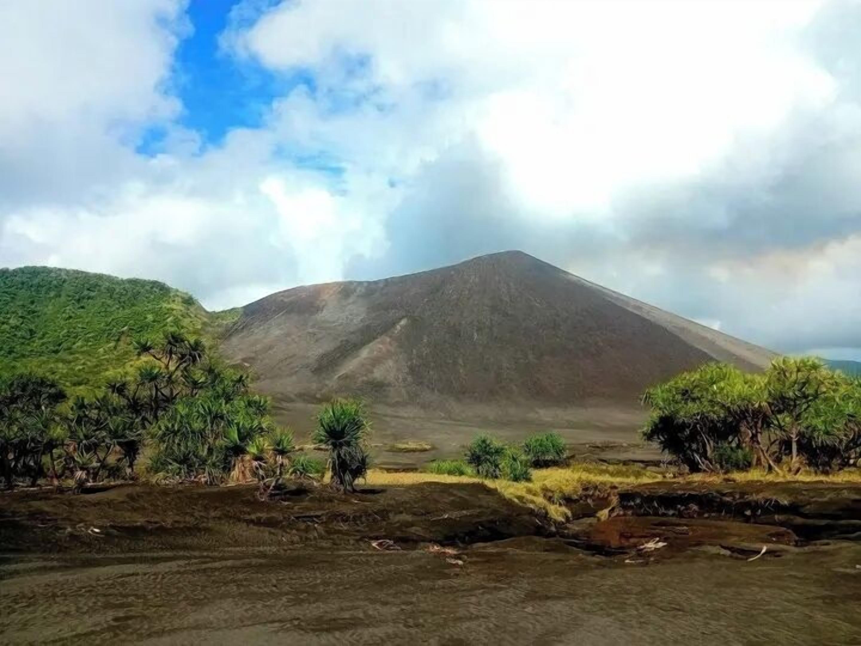 A volcanic landscape with a prominent mountain, lush greenery, and a clear sky.