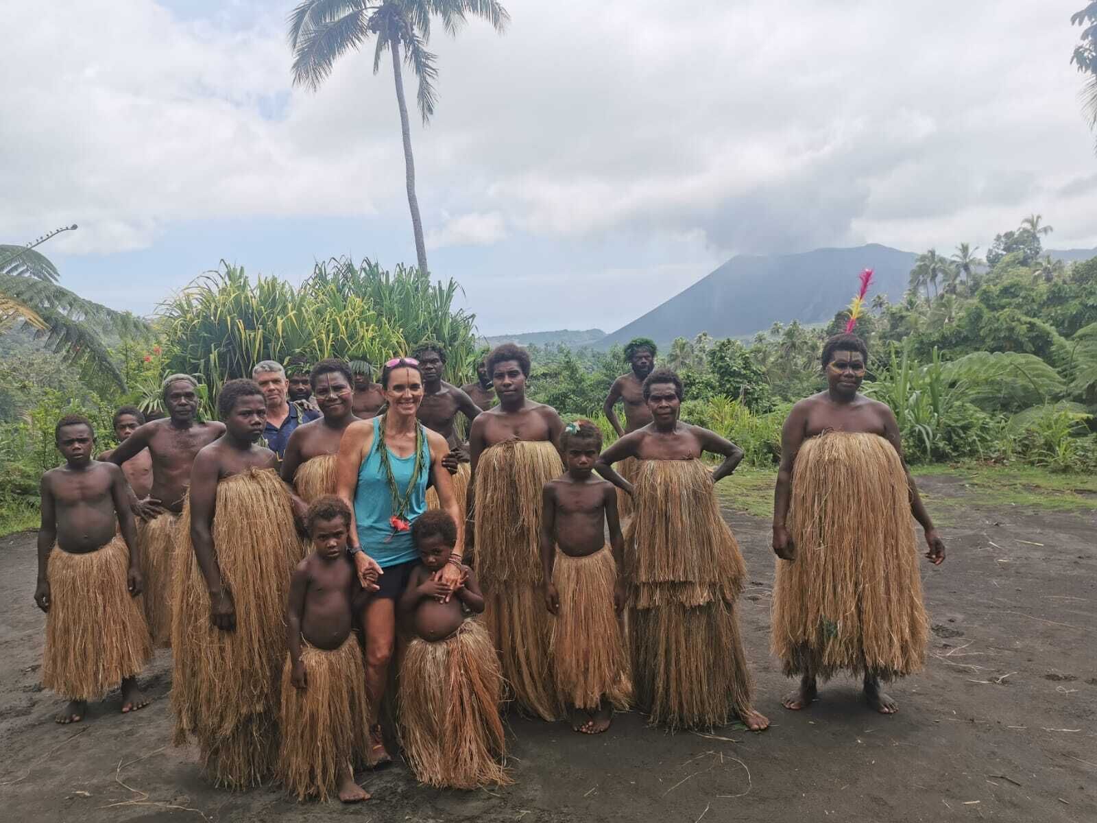 A group of people in traditional attire standing in a natural setting with a mountain in the background.