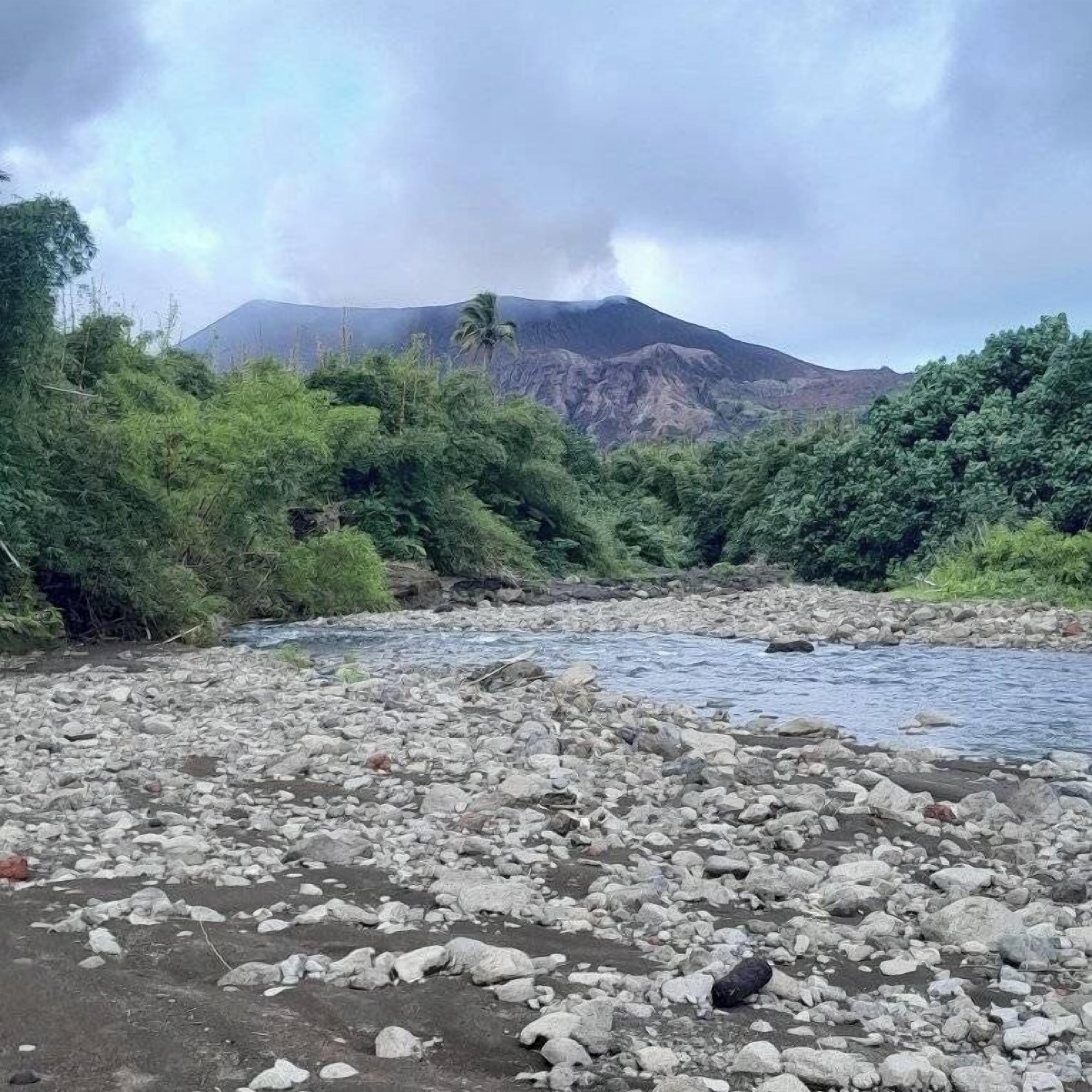 Leito de rio pedregoso com montanha ao fundo.