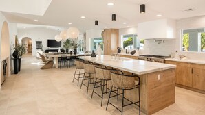 Una cocina amplia con una isla grande, taburetes de bar y un comedor.