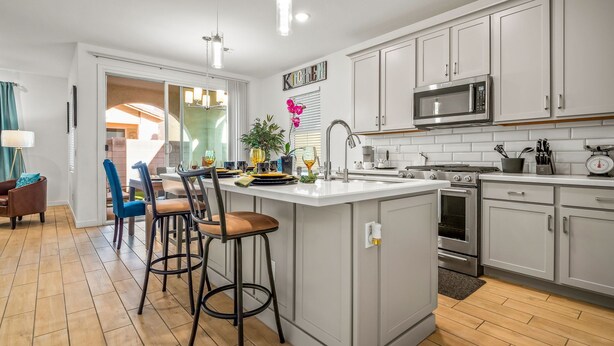 A modern kitchen with white cabinets, stainless steel appliances, and a central island with bar stools.