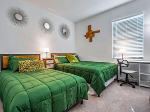 A bedroom with two beds, a desk, and a chair.