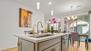 A modern kitchen with a central island, pendant lighting, and a dining area with a view.