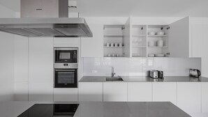 A modern kitchen with built-in appliances, including a microwave, oven, and sink, and a countertop with a kettle and toaster.