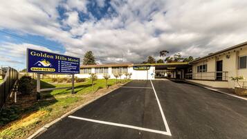Une enseigne indiquant les services proposés par un motel, un parking et un bâtiment doté d’une entrée abritée.